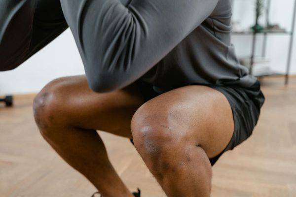 Man performing a controlled bodyweight squat in a minimalist gym.